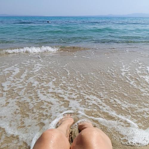 a person laying in the sand on the beach at Cozy Stone House Petrino in Kriopigi