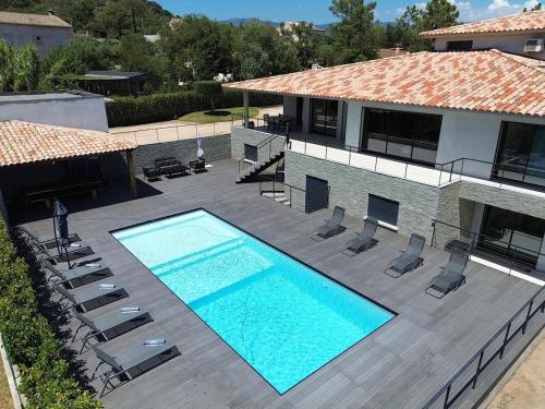 - une vue sur la piscine avec des chaises et une maison dans l'établissement Villa - Porto-Vecchio - Piscine privée, à Porto-Vecchio