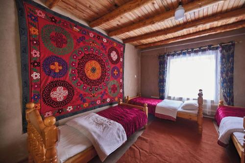 a bedroom with two beds and a red wall at Ulugbeks guesthouse in Yukary-Ukhum