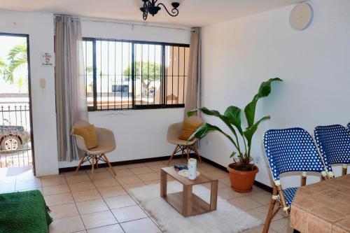 a living room with chairs and a table and a plant at Frente al mar in Puntarenas