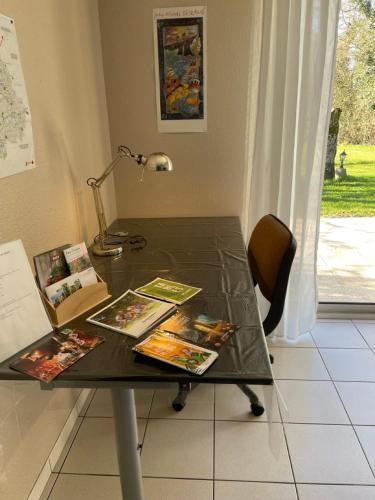 une table noire avec des livres et une lampe dans l'établissement Le Beau Repaire de Jean, à Beaurepaire