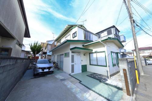 a white house with a car parked in front of it at サザンコースト湘南 in Chigasaki