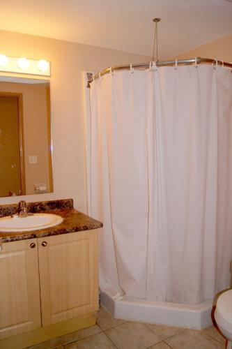 a bathroom with a white shower curtain and a sink at Hotel Laurier - Apartment Style Residence in Waterloo