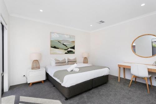 a bedroom with a bed and a desk and a mirror at Spacious and modern Dianella in Perth