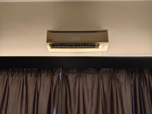 a television sitting on a wall above a curtain at Homestay B-Lagoon Ayer Keroh by AlliEyka 2 in Kampong Bukit Beruang