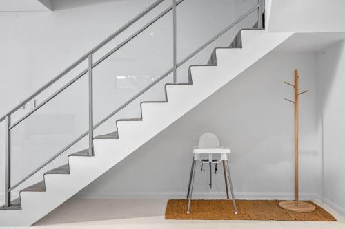 a staircase in a white room with a stool under it at Luxury Coastal Townhouse 130m to Cottesloe Beach in Perth