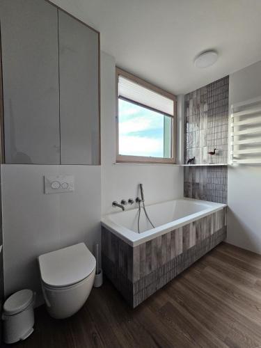 a bathroom with a tub and a toilet and a window at Gabrysiówka in Sztabin