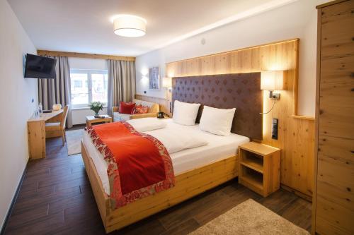 een slaapkamer met een groot bed met een houten hoofdeinde bij Hotel Victoria - adults only in Gerlos