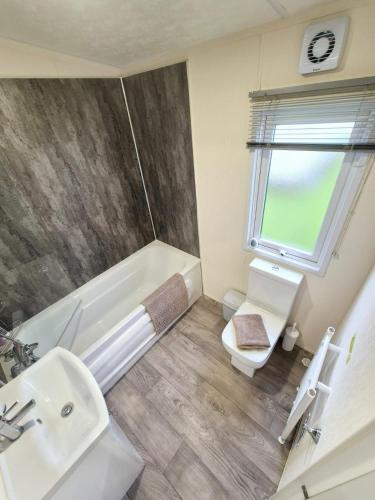a bathroom with a tub and a toilet and a sink at Whitstable Delta Superior in Seasalter