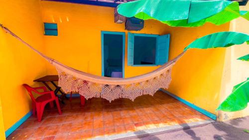 a hammock hanging from the side of a yellow house at Pousada e Hostel Recanto das Estrelas in Marau