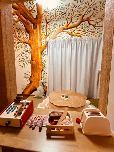 a wooden table with a tree mural on the wall at 8Home Kids House in Osaka