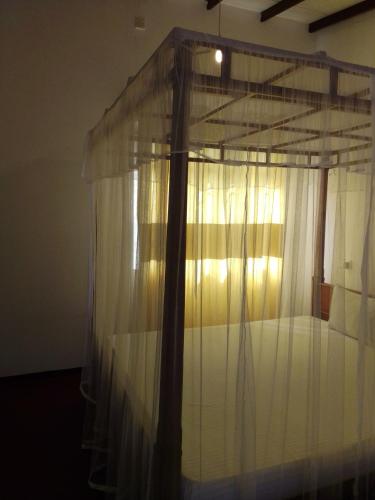 a bedroom with a canopy bed with white curtains at Pravindi Guest Home in Mirissa