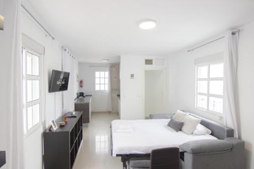 biały pokój z łóżkiem i kanapą w obiekcie RentalSevilla Guadalete I w Sewilli