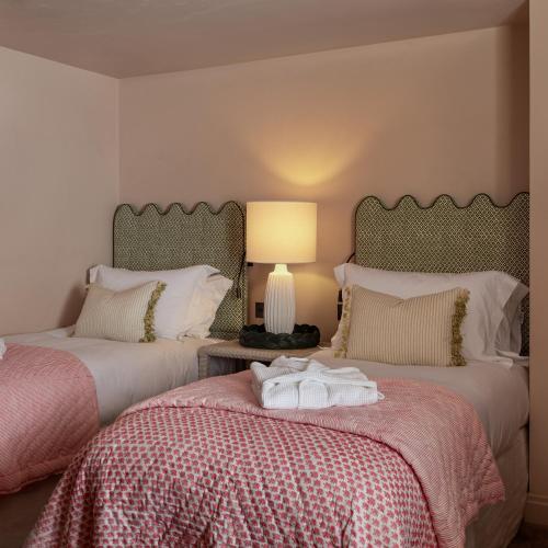 a bedroom with two beds and a lamp on a table at Louma Country Hotel in Wootton Fitzpaine