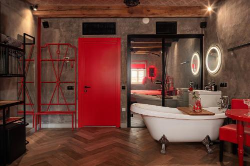 a bathroom with a red door and a bath tub at Masoch. Hotel & Cafe in Lviv