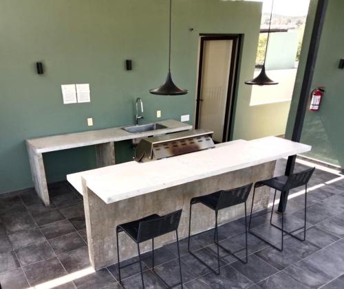 a kitchen with a counter and a sink and chairs at Relajante y acogedor in Tangolunda