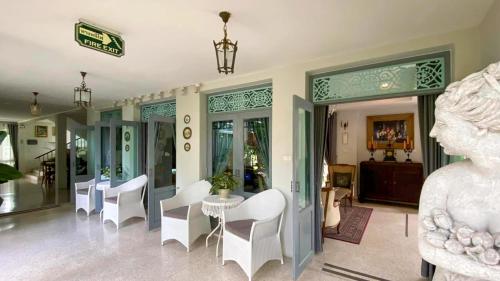 a room with white chairs and a table and a statue at Villa Amphawa in Amphawa