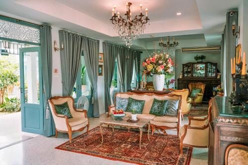 a living room with a couch and chairs and a chandelier at Villa Amphawa in Amphawa