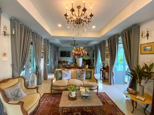 a living room with a couch and a chandelier at Villa Amphawa in Amphawa