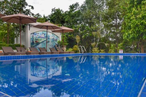 a swimming pool with chairs and umbrellas next to it at Villa Amphawa in Amphawa