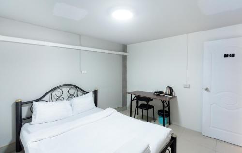 a white bedroom with a bed and a table at Mitr Inn Nimman in Chiang Mai
