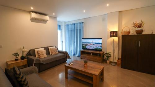 a living room with a couch and a television at Apartamento a 50 metros do Santuário de Fátima in Fátima