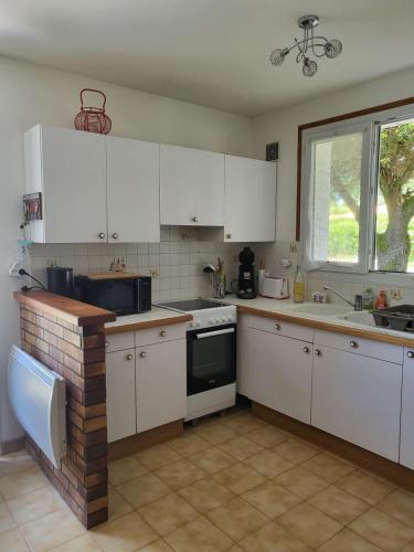 une cuisine avec des armoires blanches, un évier et une fenêtre dans l'établissement Maison bord de mer, à Saint-Pierre-dʼOléron