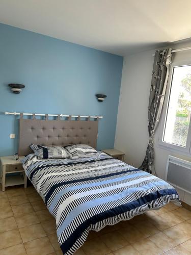 une chambre avec un grand lit avec un mur bleu dans l'établissement Maison bord de mer, à Saint-Pierre-dʼOléron