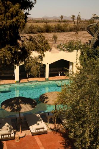 an overhead view of a swimming pool with chairs and trees at Jenan Mayshad Marrakech, Boutique hotel with Pool & Private Padel Court in Marrakech