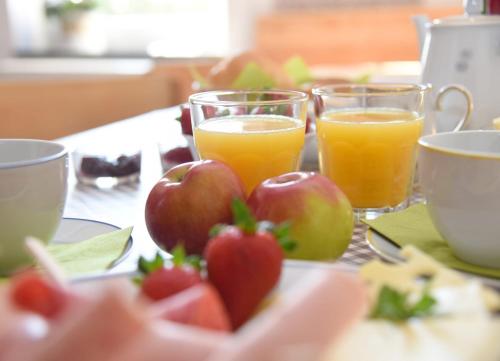 two glasses of orange juice and apples on a table at Gästehaus Wagner in Chemnitz