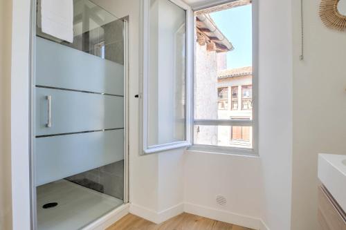 a glass cabinet in a bathroom with a window at Apparts Limogeanne - Clim - Centre historique in Périgueux