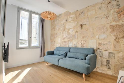 a blue couch in a room with a stone wall at Apparts Limogeanne - Clim - Centre historique in Périgueux