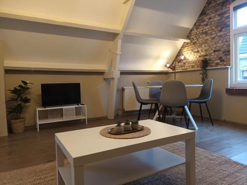 a living room with a table and chairs and a tv at attic apartment in the center in Gouda