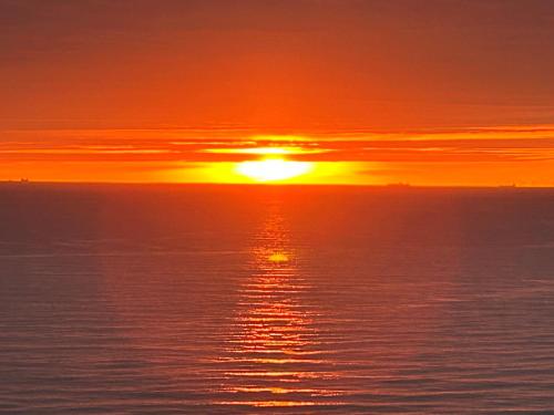 a sunset over the ocean with the sun setting at Palace Hotel Zandvoort in Zandvoort