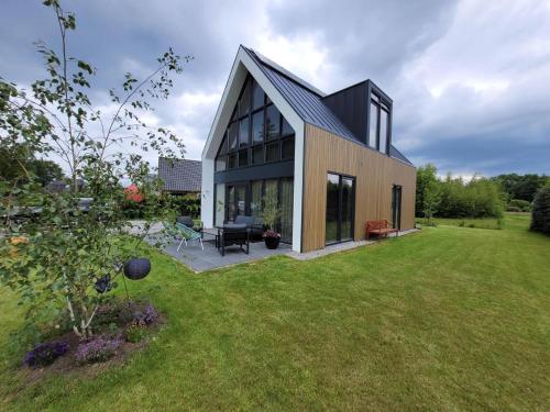 a house with a black roof on a yard at Villa Bosanemoon with Sauna | 6 persons in Gasselte