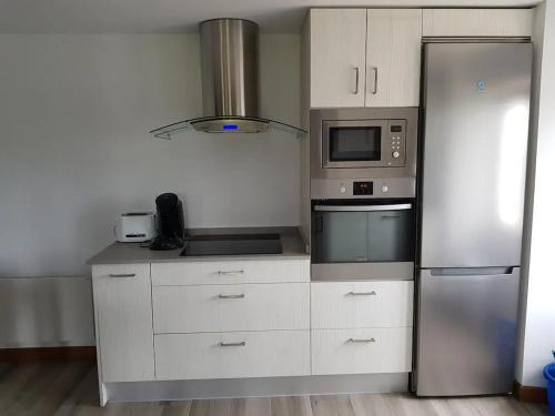 a kitchen with white cabinets and a stainless steel refrigerator at Appartement charmant à Sare avec vue sur la montagne in Sare
