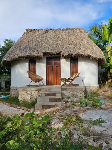 a small hut with two chairs in front of it at Cabaña Los Gallitos Ecolodge in Sacalum