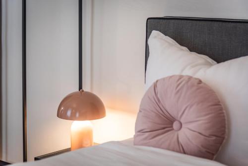 a bed with a pink pillow next to a lamp at Luxury Design Apartments in City Center in Graz