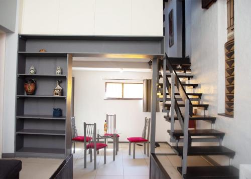 a living room with a staircase and red chairs at Linden Guest House in Johannesburg