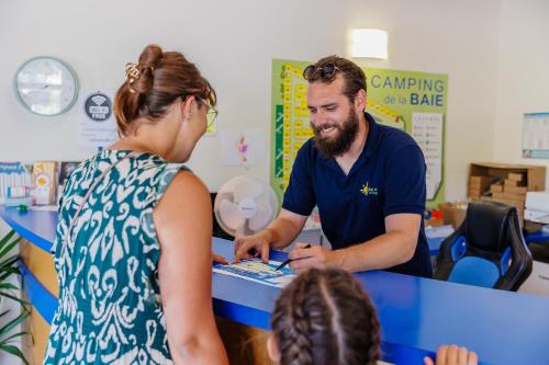 Un homme assis à une table et parlant à une femme dans l'établissement Camping Bel Air Village La Baie, à LʼAiguillon-sur-Mer