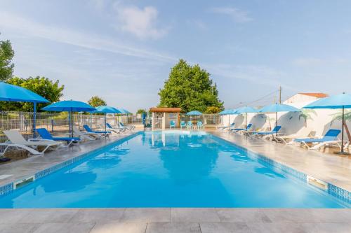 une piscine avec chaises et parasols dans l'établissement Camping Bel Air Village La Baie, à LʼAiguillon-sur-Mer