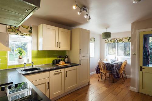 a kitchen with white cabinets and a table in it at Eira's Cottage in Nolton