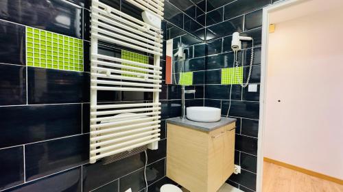 La salle de bains est pourvue de murs carrelés noirs et d'un lavabo. dans l'établissement L'horizon bleu - Vue mer - Berck-sur-mer, à Berck-sur-Mer