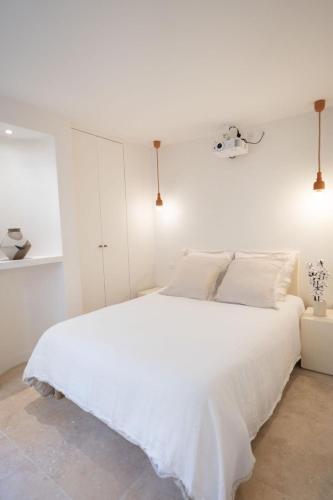 - une chambre blanche avec un grand lit et des draps blancs dans l'établissement Le cocon parisien by ecoflats, à Paris