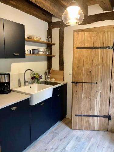 - une cuisine avec un évier et une porte en bois dans l'établissement Gîte Sidonie, à Apremont