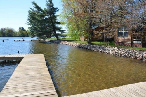 a wooden dock on a lake with a house at Minoqua Shores Cabin 6 in Minocqua