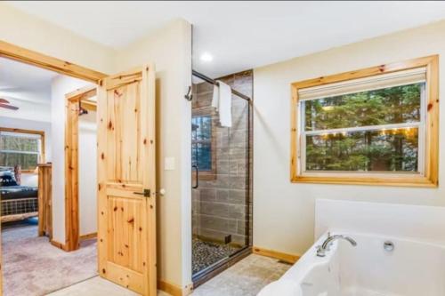 a bathroom with a tub and shower and a window at Lakeside Lookout Little Arbor Vitae Lakes in Woodruff
