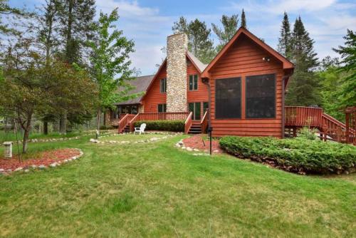 a log home with a large yard in front of it at Big St Lodge on Big St Germain Lake in Saint Germain