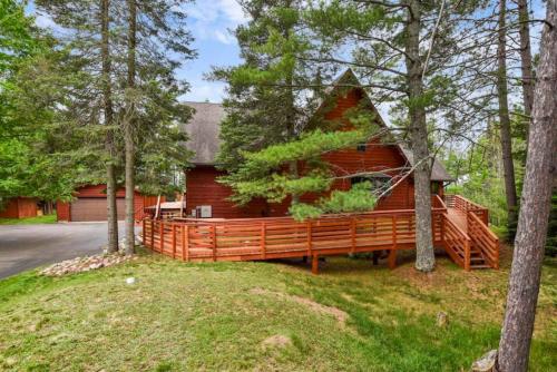 a home with a large wooden house with trees at Big St Lodge on Big St Germain Lake in Saint Germain