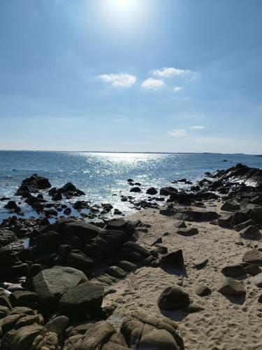 a rocky beach with the ocean in the background at Loctycaz Appartement avec jardin in Locmariaquer